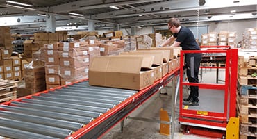 mand arbejder fra translyft arbejdsplatform i lager